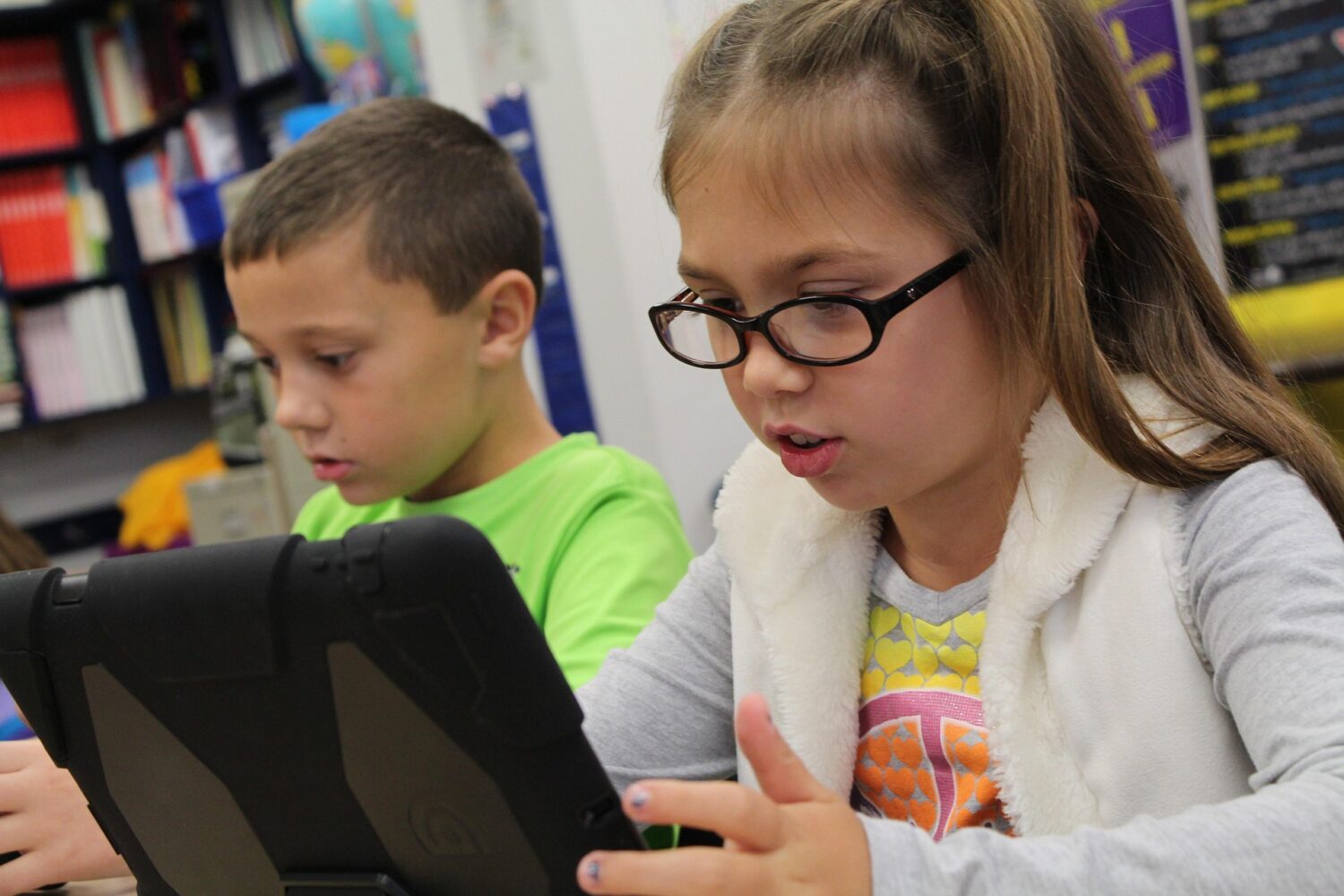 Elementary school boy and girl looking at tablet in class
