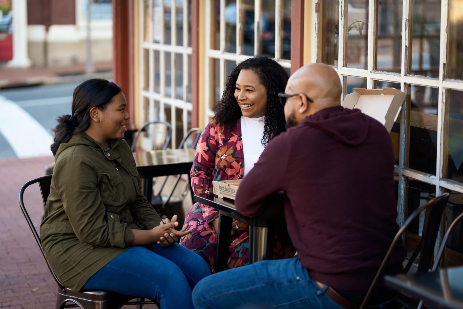 Family of three sitting at a table outside