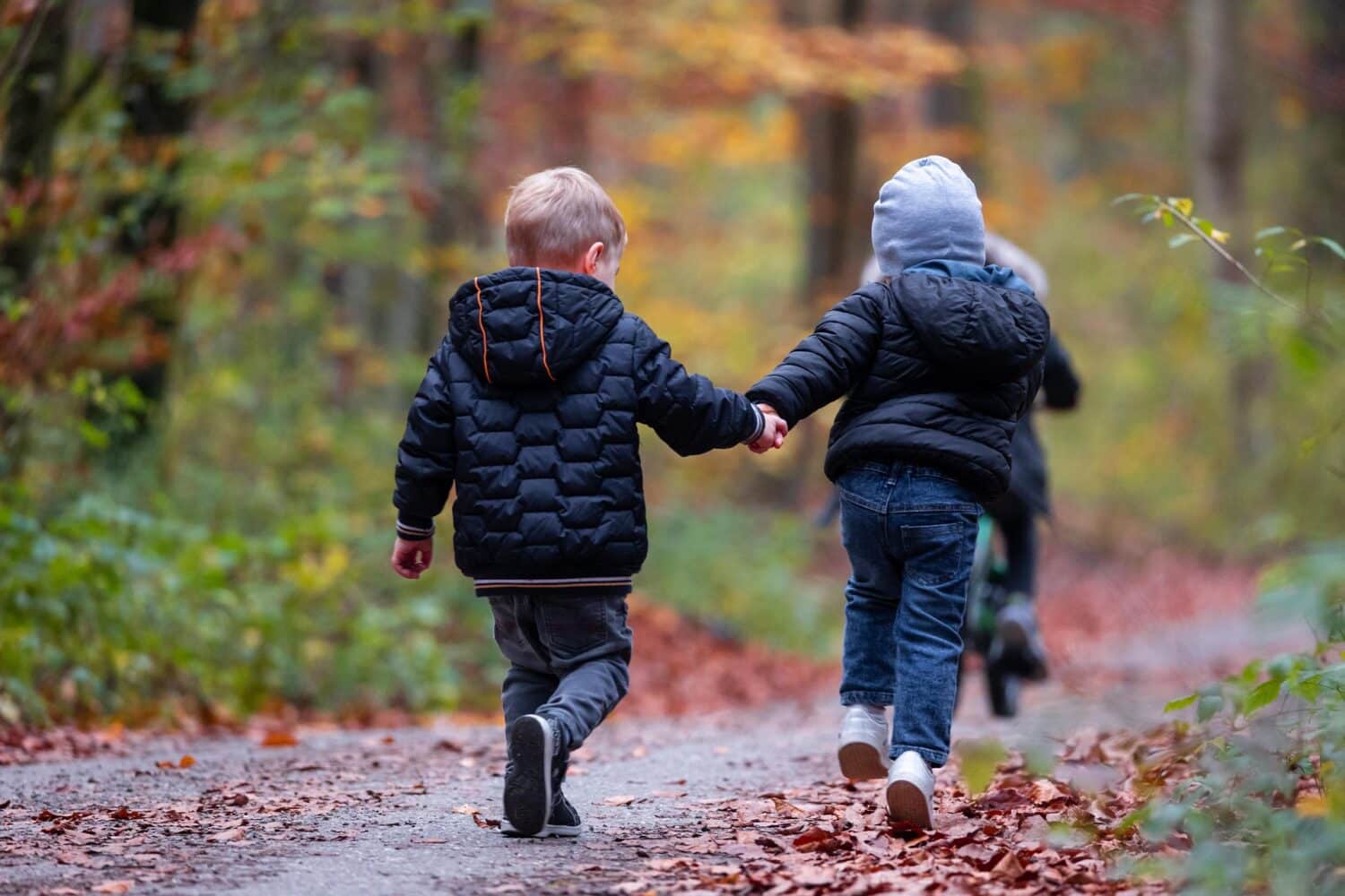 Two young kids walk outside holding hands