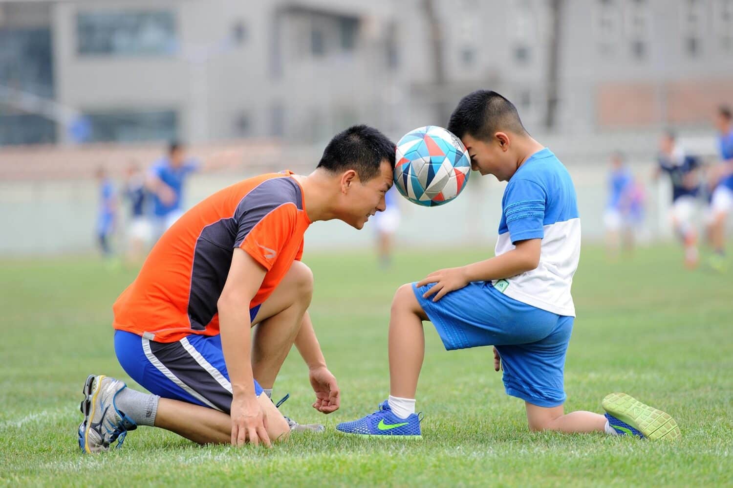 Boy and father hold soccer ball with their heads