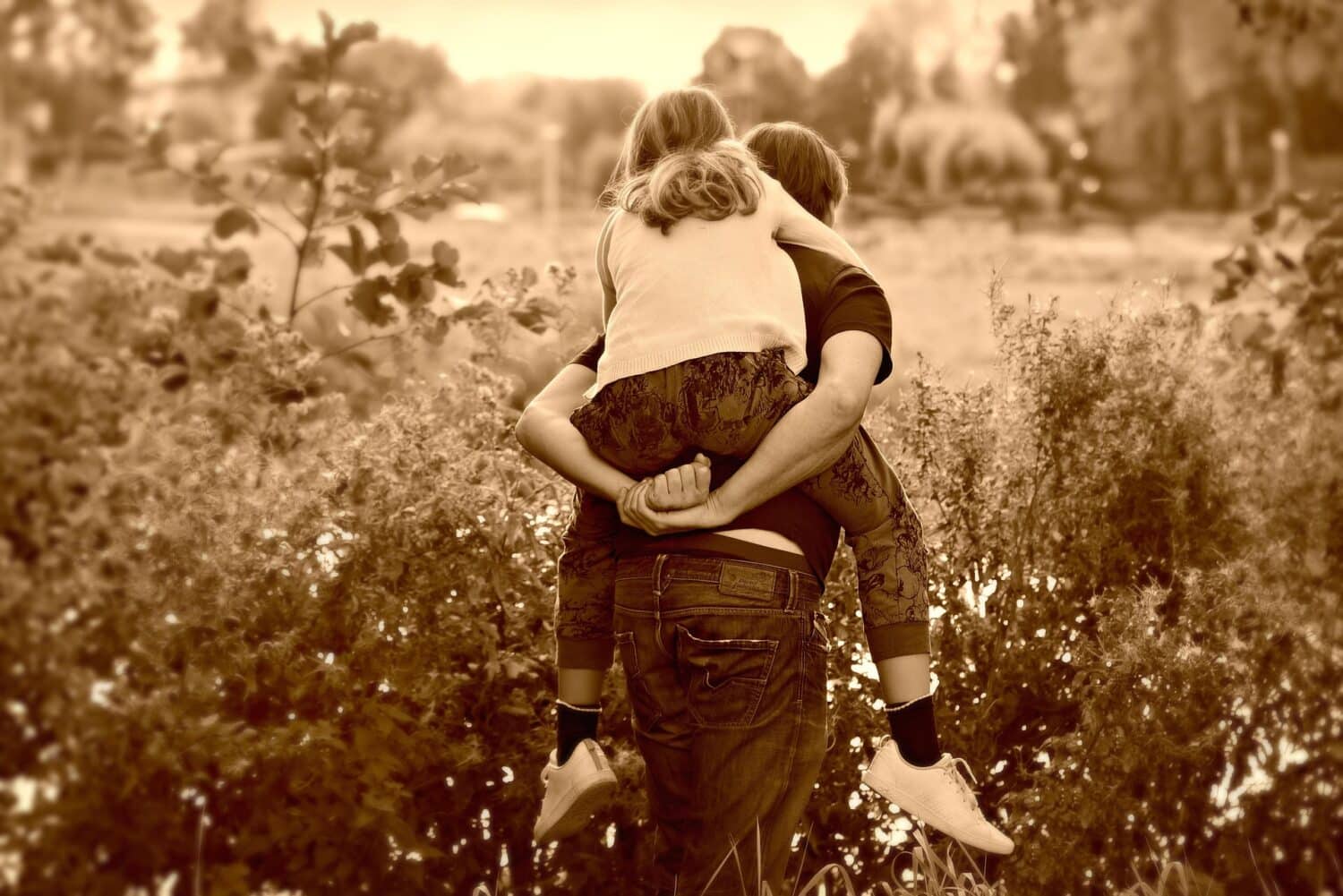 Man carries school-age child on his back in a field