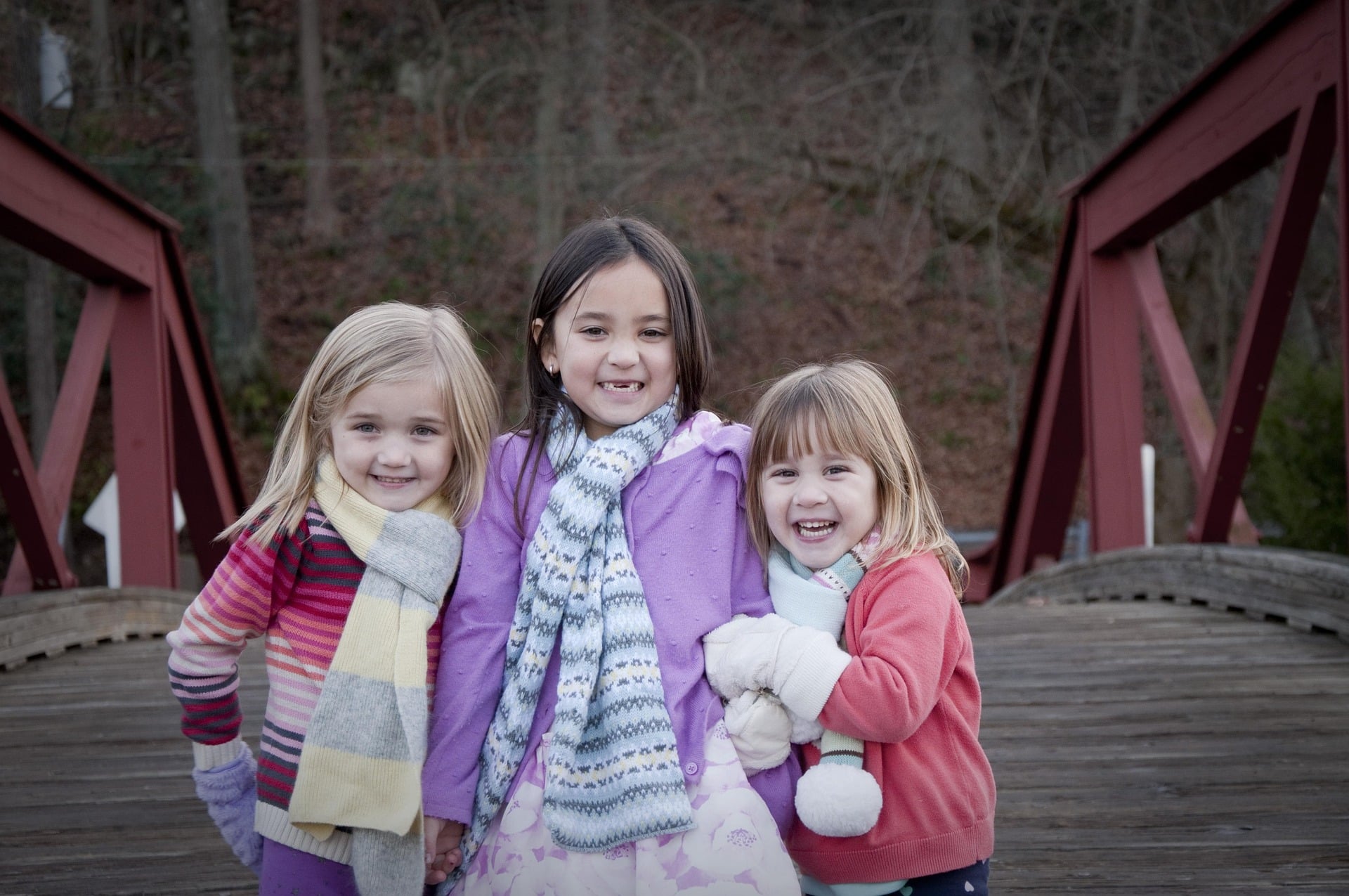Three girls dressed for cold weather smile at camera