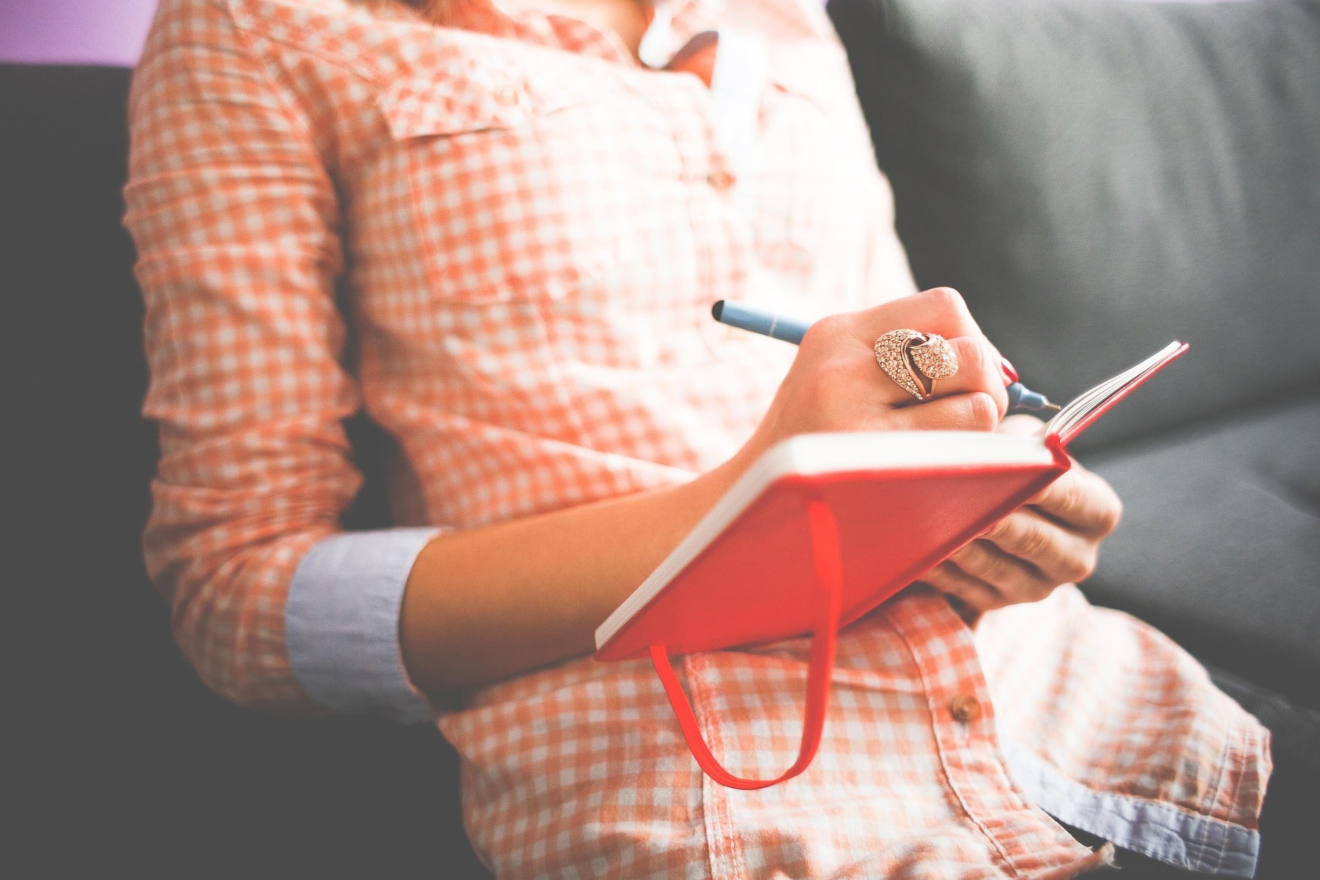 Photo of a woman writing in a red journal