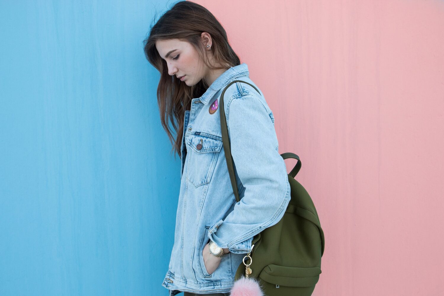 Teen girl leaning against a wall, carrying a backpack