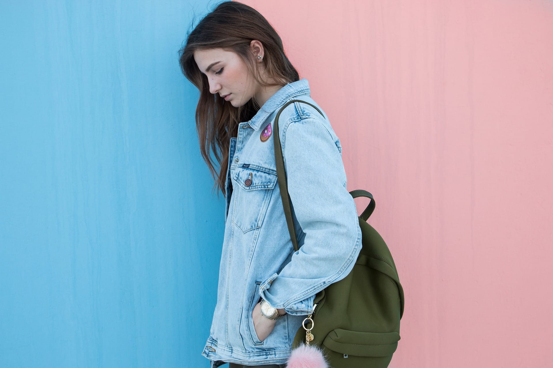 Teen girl leaning against a wall, carrying a backpack