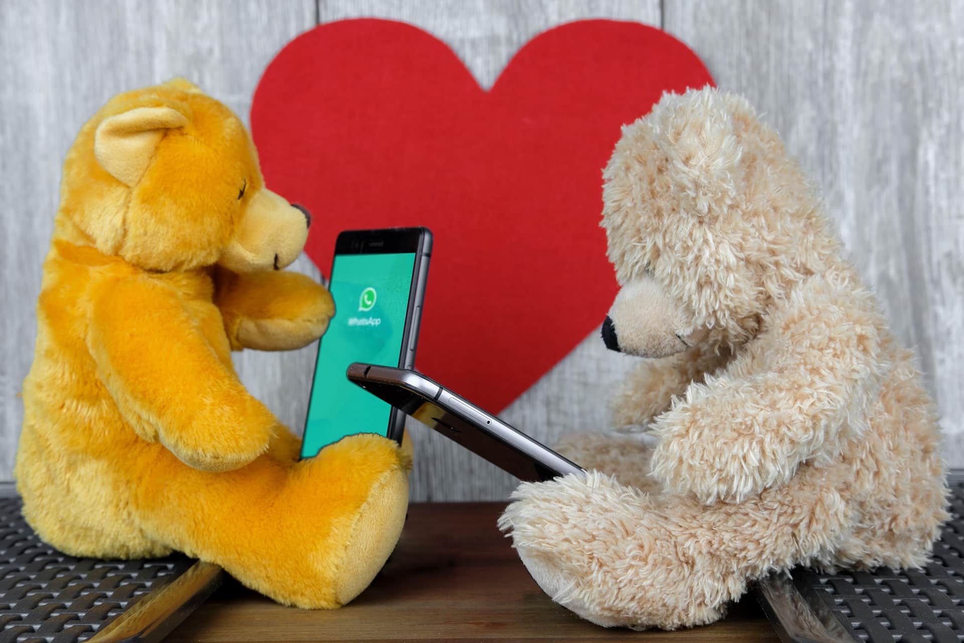 Two stuffed teddy bears holding smart phones