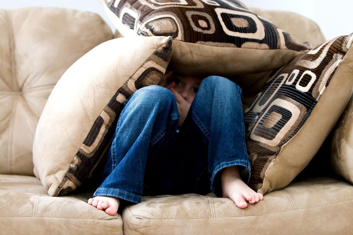 Boy hiding in a pillow fort on a couch