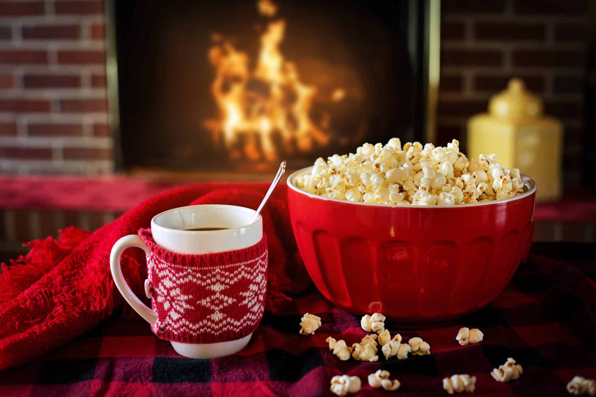 Cozy home scene with mug and popcorn in front of fireplace