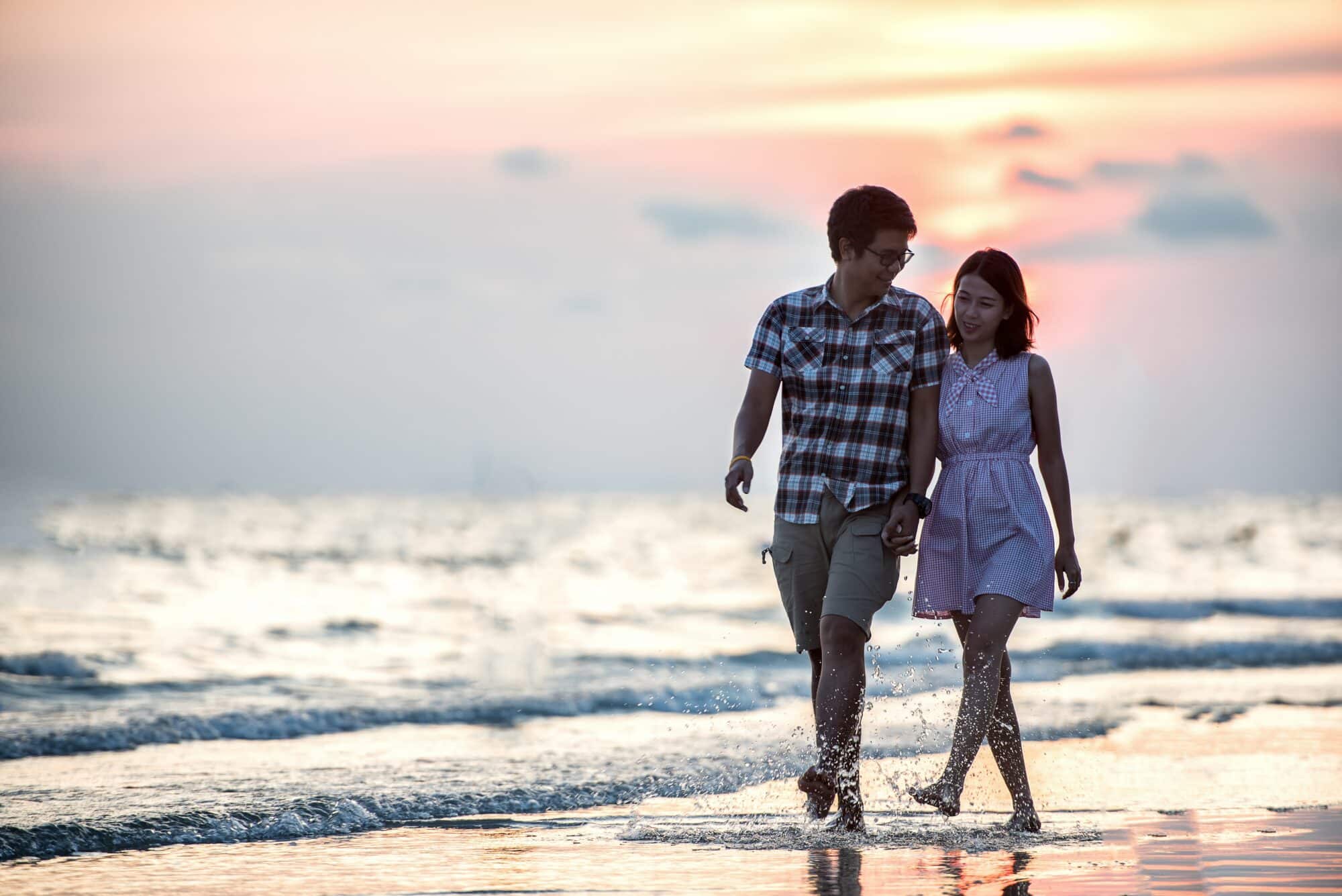 Smiling couple walks on beach
