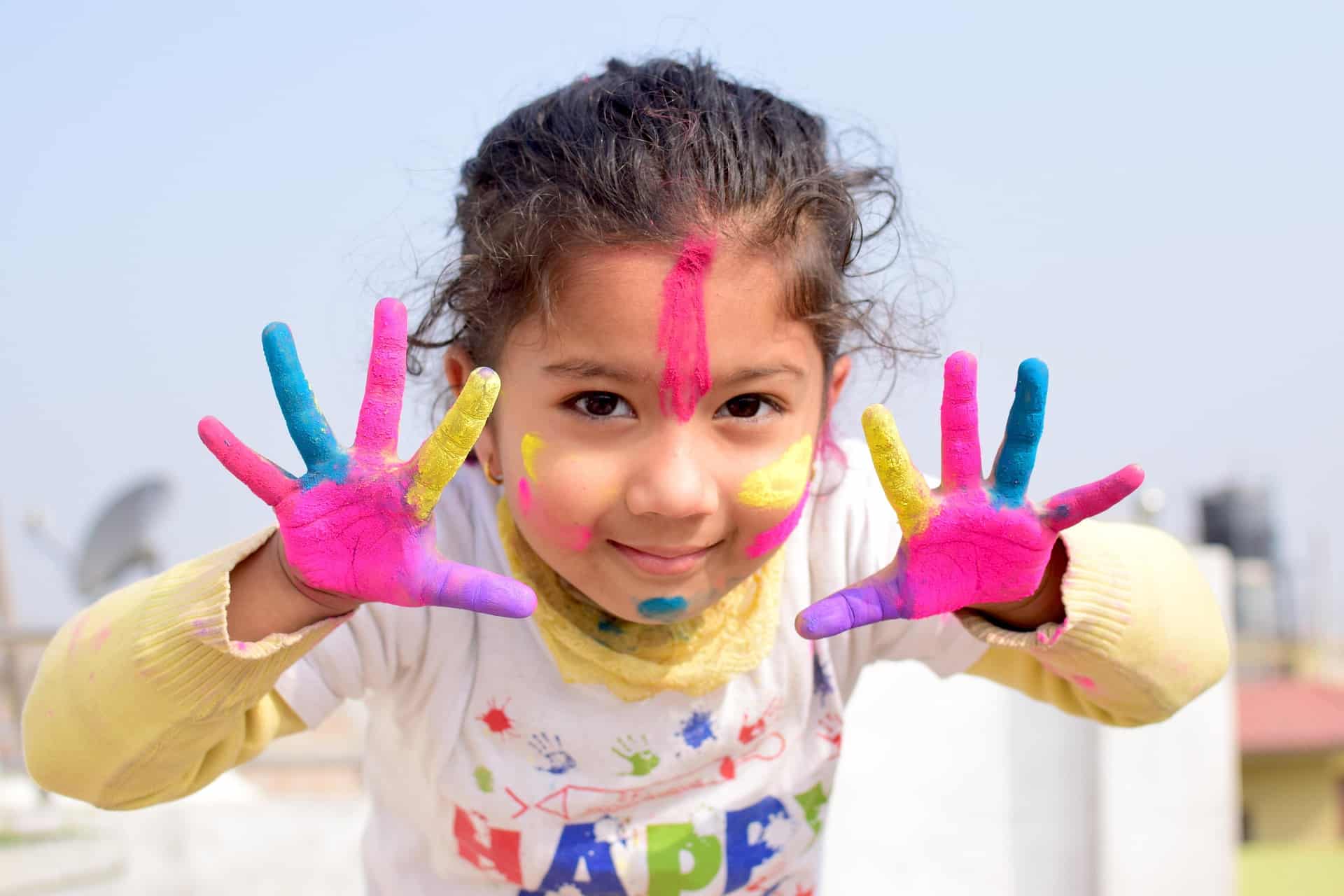 Young girl with finger paint on hands and face